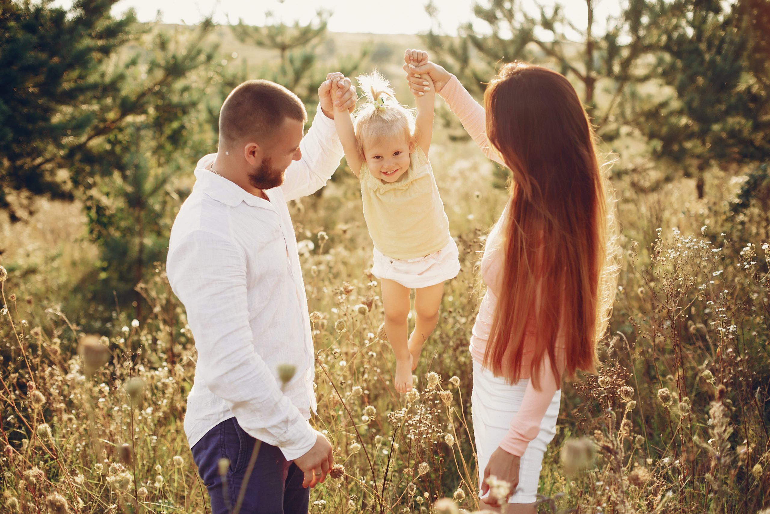 Cute family in a field. Beautyful mother with her little daughter. Hundsome man with wife